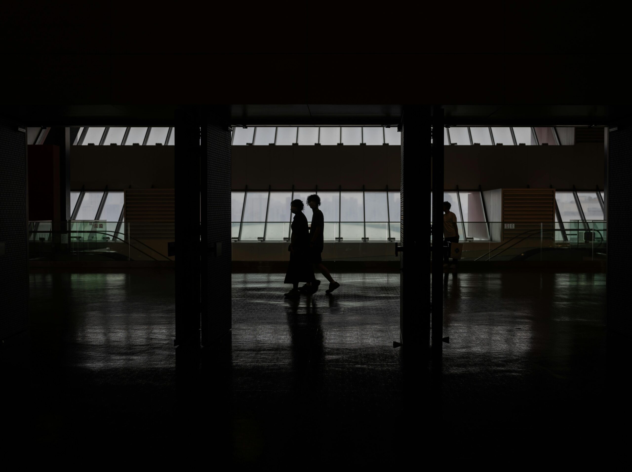 Silhouette of people walking through a modern hallway with large windows in Shanghai, China.