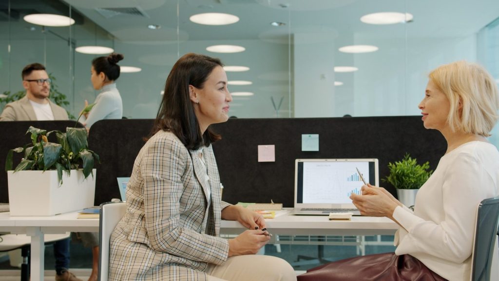 Two women talking at a desk in an office