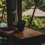 A man sitting at a table using a laptop computer
