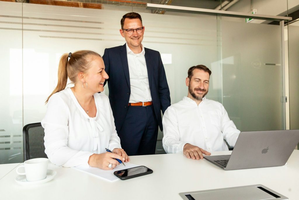 Three HR colleagues collaborating around a laptop in an office