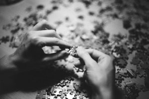 grayscale photo of person holding puzzle piece